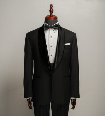 Black tuxedo with white shirt and bow tie on a mannequin against a gray background