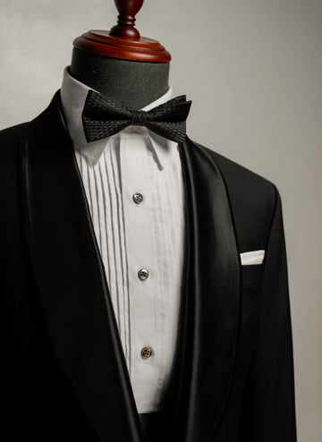 Black tuxedo with a bow tie on a mannequin against a neutral background