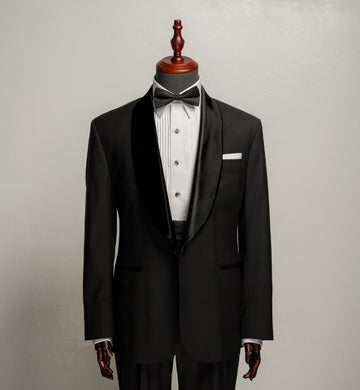 Black tuxedo with white shirt and bow tie on a mannequin against a gray background