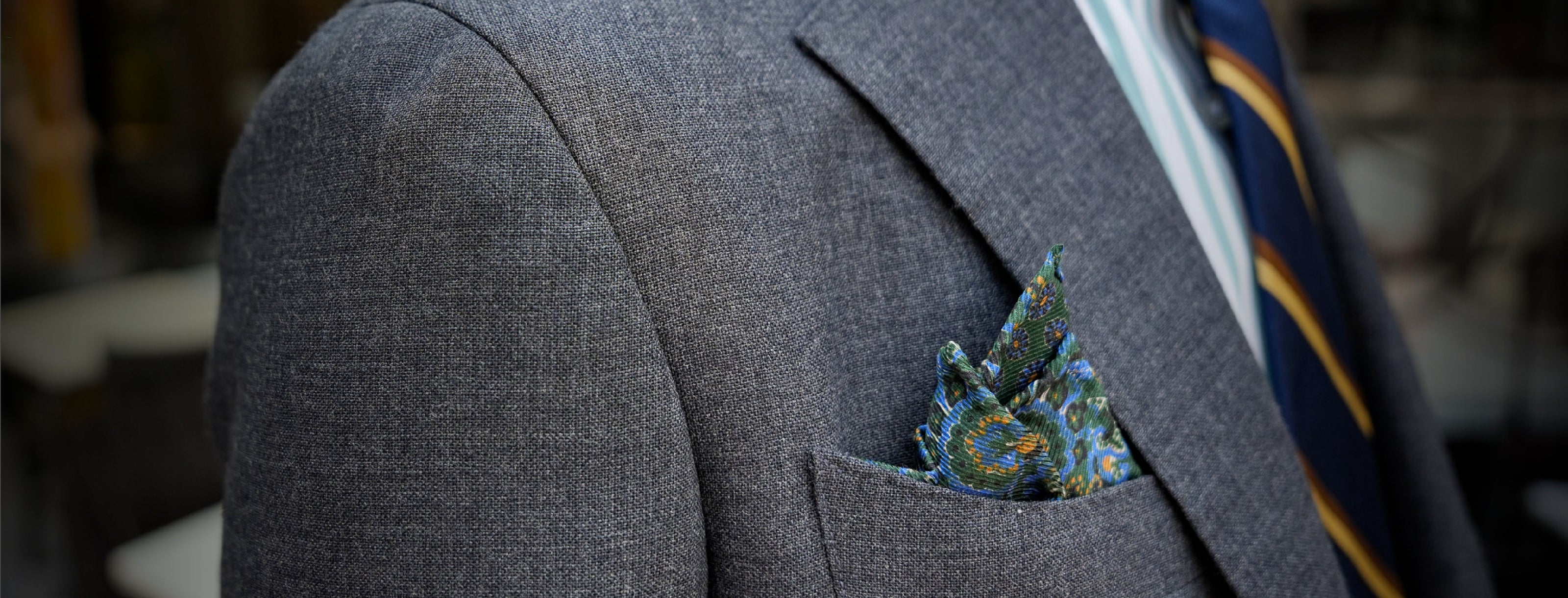 Gray suit jacket with a patterned pocket square and tie.