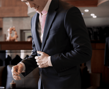 Man adjusting his suit jacket in a clothing store.