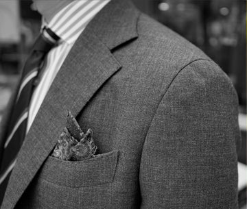 Gray suit with a pocket square and striped tie.