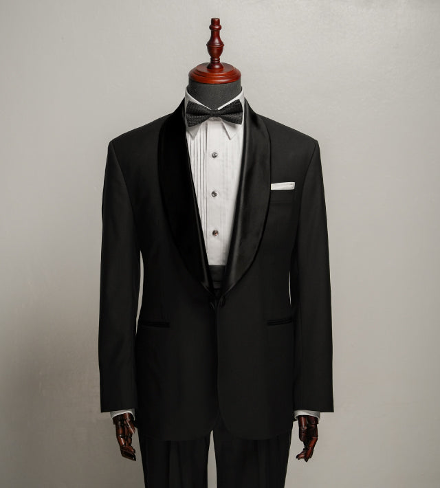 Black tuxedo with white shirt and bow tie on a mannequin against a gray background