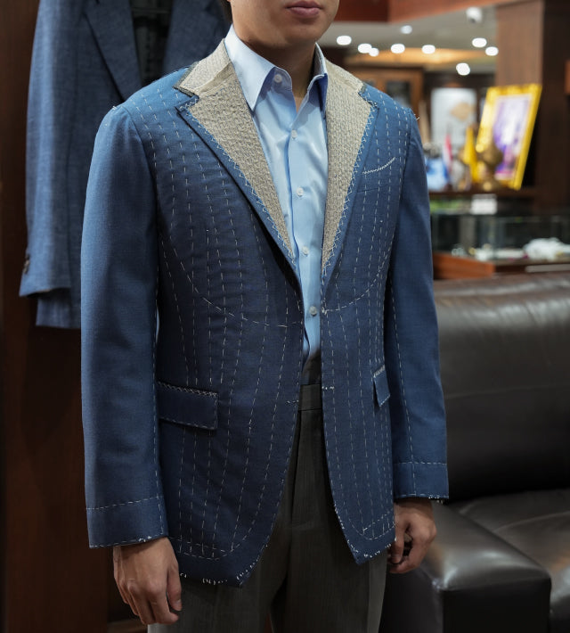 Person wearing a blue textured blazer over a light blue shirt in an indoor setting.