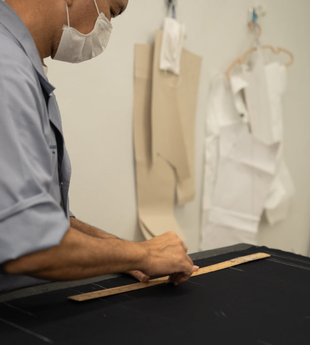 Person measuring fabric on a cutting table in a sewing or design studio.
