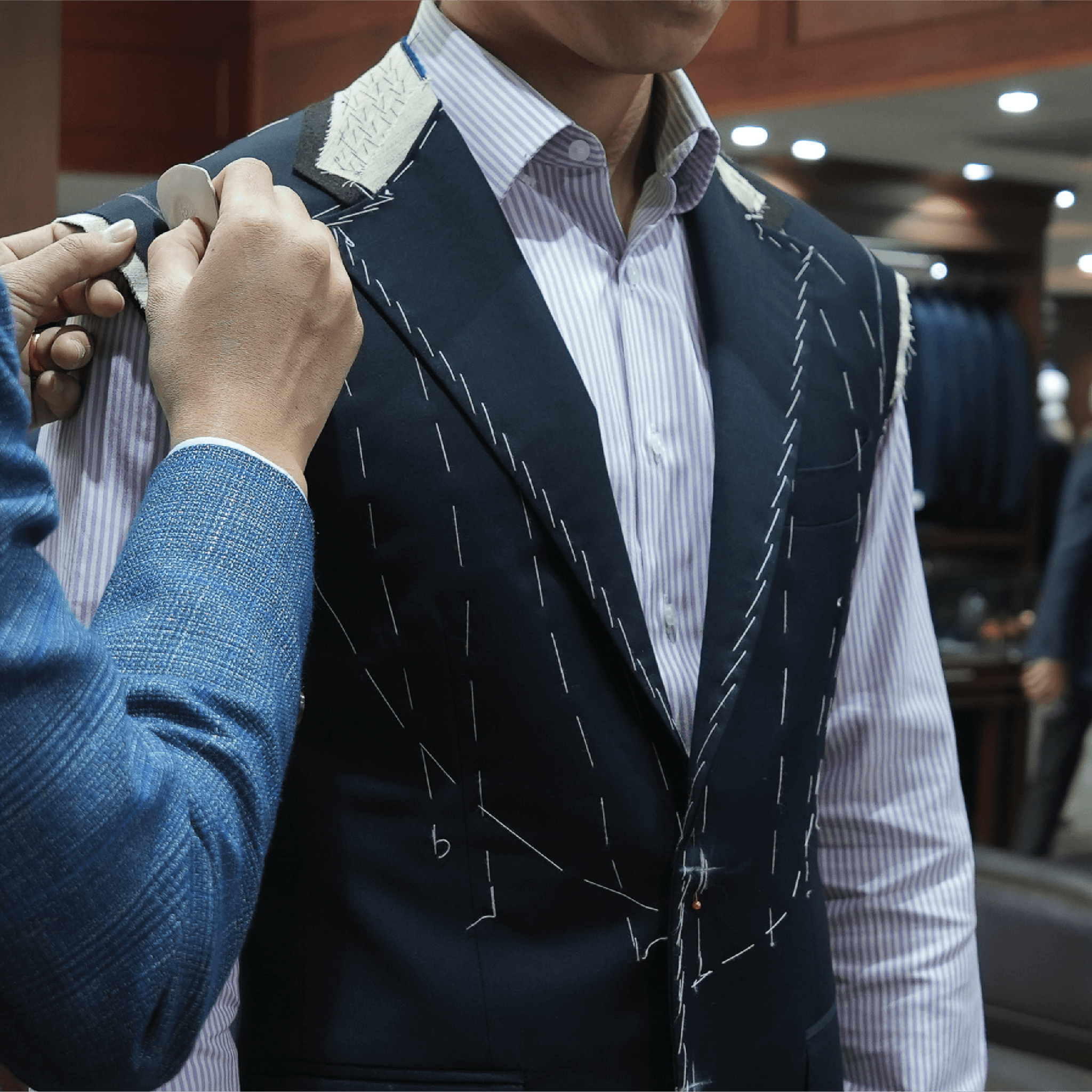 Person adjusting a suit jacket in a fitting room.