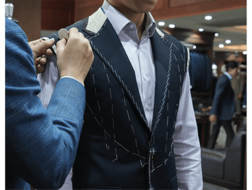 Person adjusting a suit jacket in a fitting room.