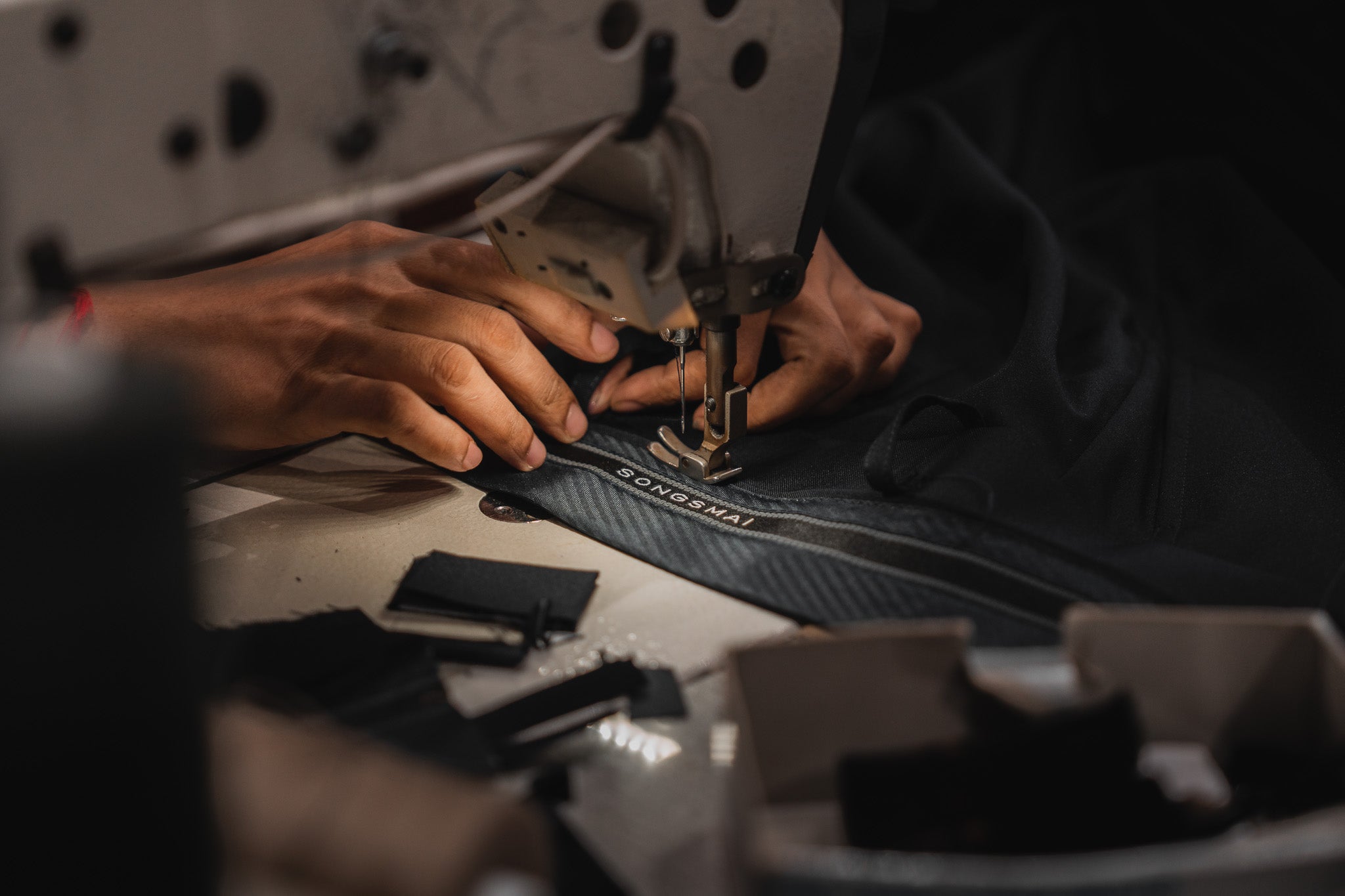 Person sewing leather in a workshop setting.