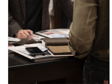 Person interacting with a table displaying various items including a phone and wallets.