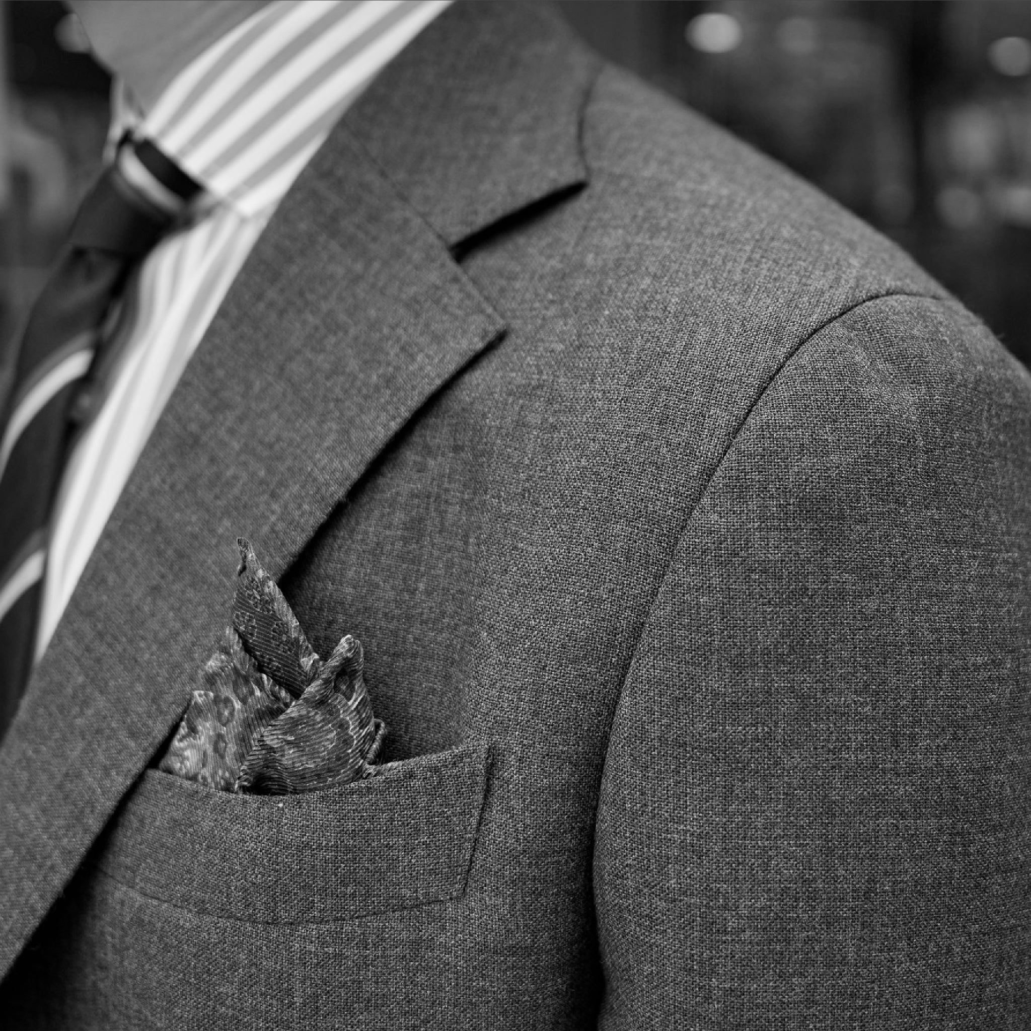 Gray suit with a pocket square and striped tie.